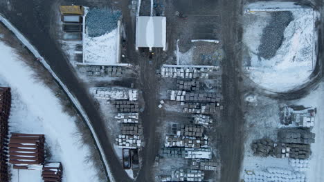 Top-down-aerial-of-forklifts-working-on-recycling-plant-in-winter