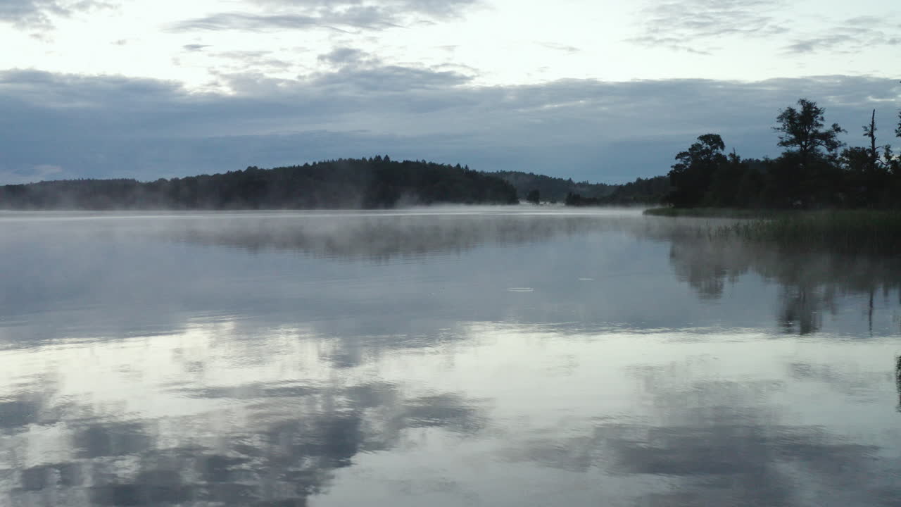 4k 무인 항공기가 안개가 낀 호수의 수면 가까이에서 천천히 날아갑니다.