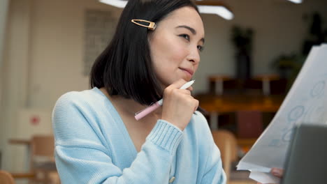 Una-Mujer-De-Negocios-Sonríe-Mientras-Consulta-Documentos-De-Trabajo-En-Una-Cafetería-1