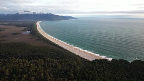 long sandy beach with turquoise sea and coastal forest at bruce bay on west coast of new zealand. aerial shot