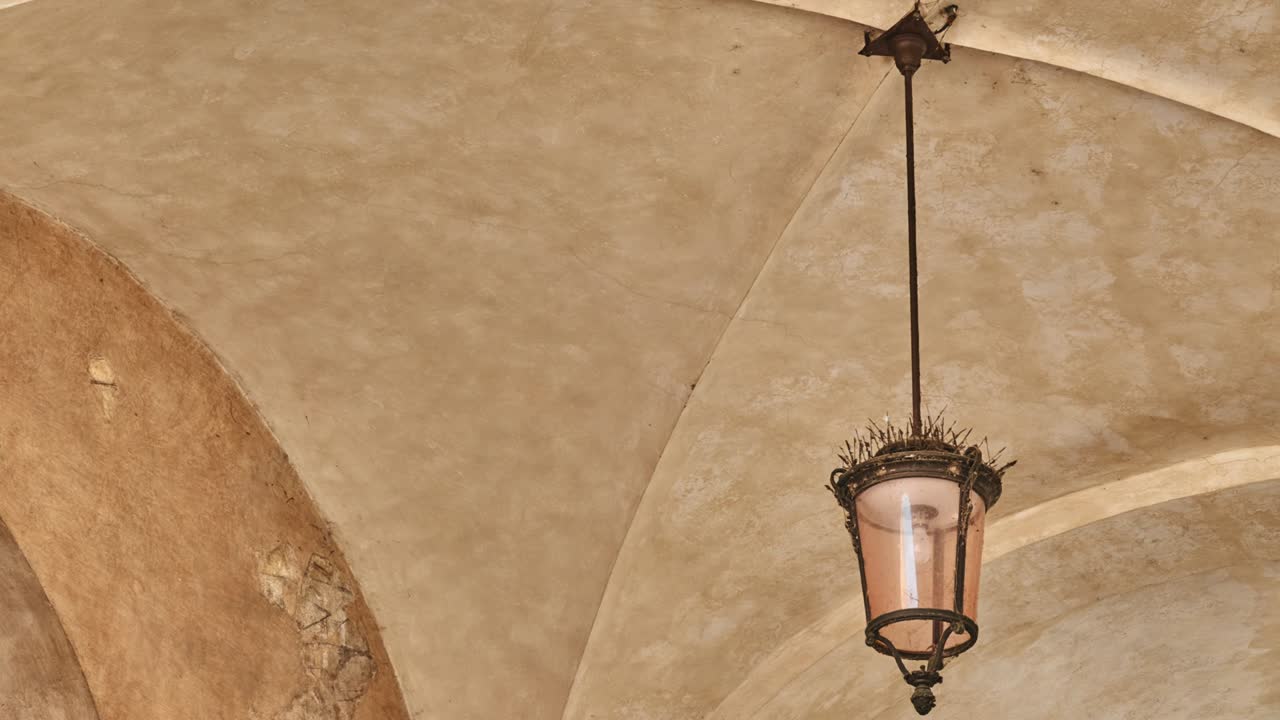 bucle de cinemagraph: lámpara colgante cuelga en arco a un edificio antiguo y se balancea en el viento