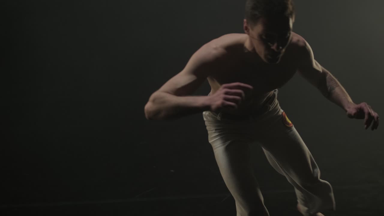 Capoeira fighters performing dynamic moves on stage. Martial arts, dance, and acrobatics in action. Bare-chested athletes showcasing strength, flexibility, and technique under spotlights