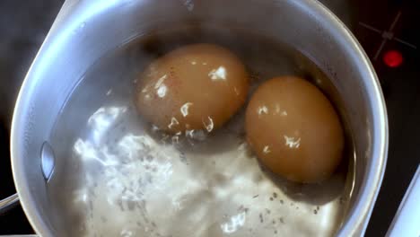 close up of 2 eggs boiling in a pan