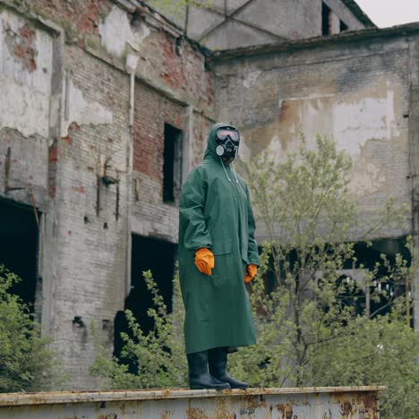 Survivor in protective chemical suit. Person in infected zone standing alone on the background of empty ruined building. Air pollution