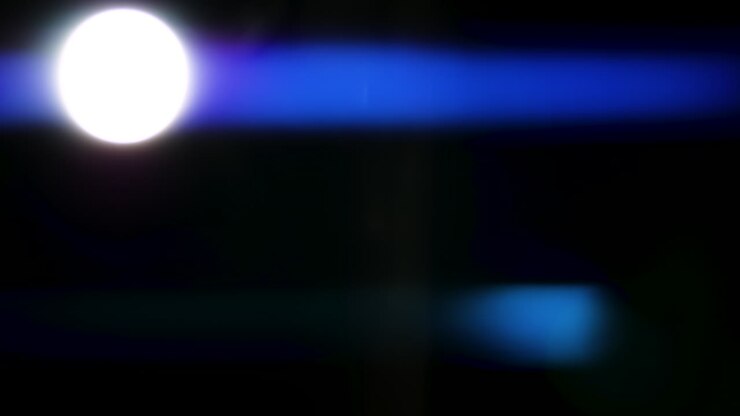 Bellissimi, sbalorditivi riflessi di luce e strisce anamorfiche blu girati su sfondo nero con lente anamorfica cinematografica di alta gamma, come sfondo, overlay di light leak o transizioni per editor