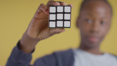 studioporträt eines kleinen jungen auf asd-spektrum, der einen puzzlewürfel auf gelbem hintergrund löst 6