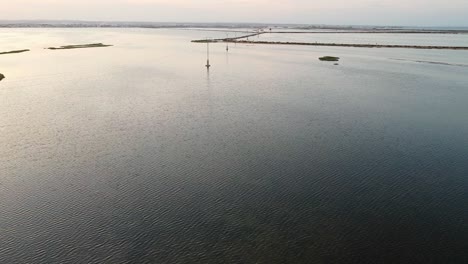 Drohnenaufnahme-Von-Stromleitungen,-Die-Durch-Eine-Flache-Wasserbucht-Führen