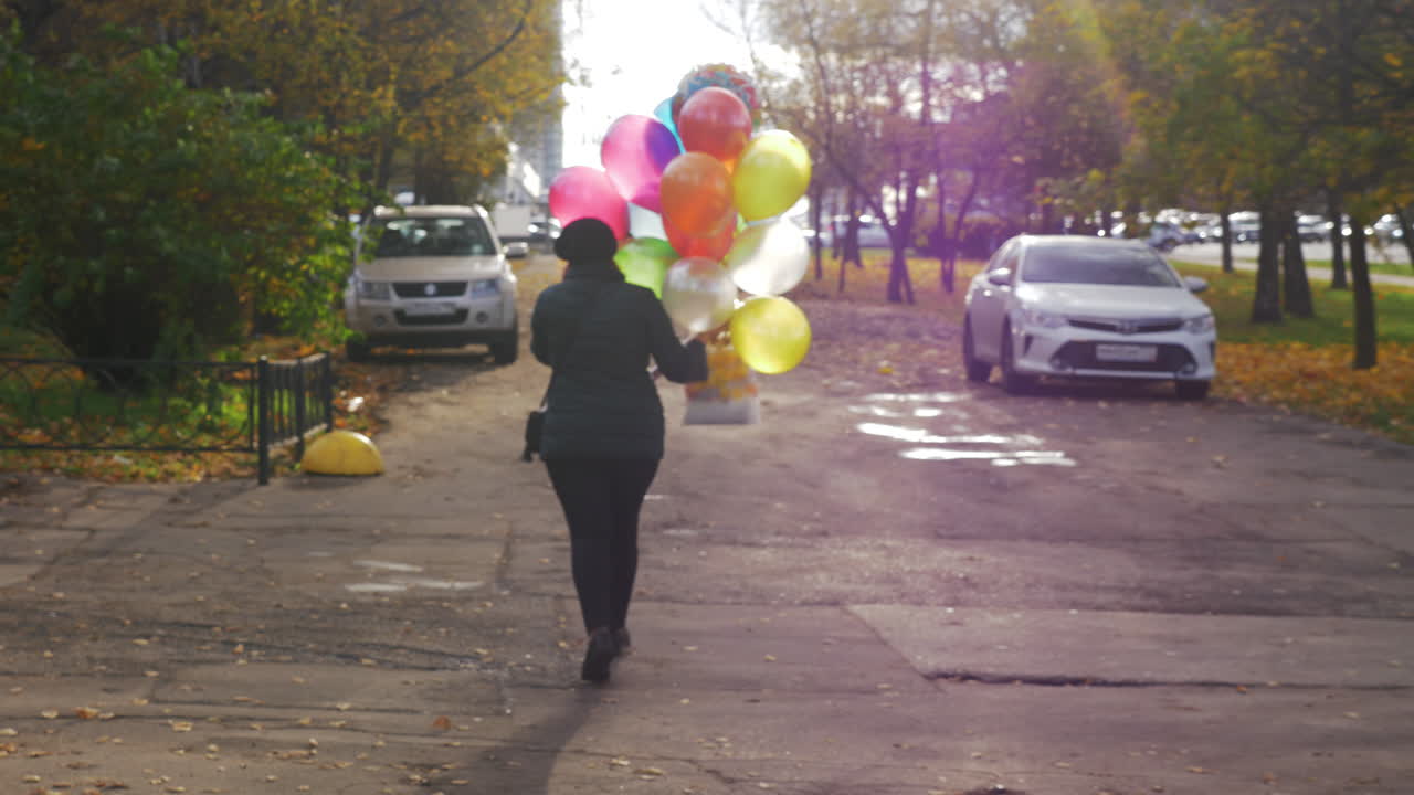 un movimiento lento de una mujer caminando por la calle con globos coloridos