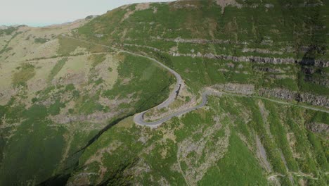 Drone-upward-crane-reveal-sharp-Madeira-hairpin-turn-on-lush-mountain-cliff