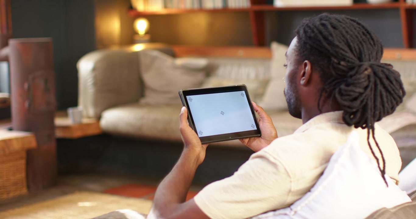 African American man in living room, adjusting tablet tilt prompted by loading screen, copy space