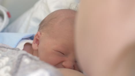 newborn baby with mom lying under the blanket