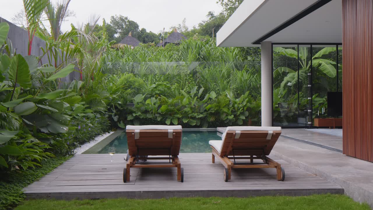 Relaxing time by the pool in a garden setting in bali with loungers