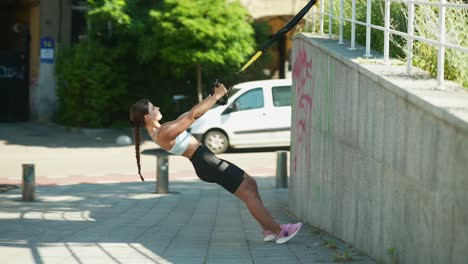 mujer haciendo ejercicio trx al aire libre