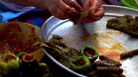 a woman is preparing stuffed grape leaves, leaf wrap, turkish food culture and stuffed leaves