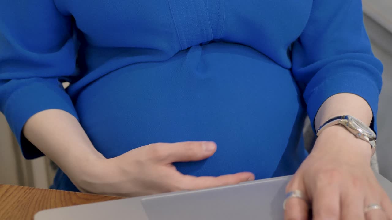 임신한 백인 여성이 노트북에서 연구하고 있습니다.