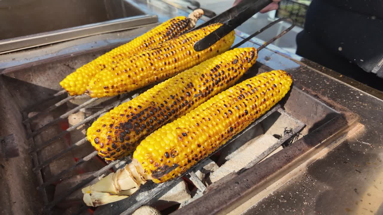 Turning Golden Corn Cobs on an Outdoor Grill