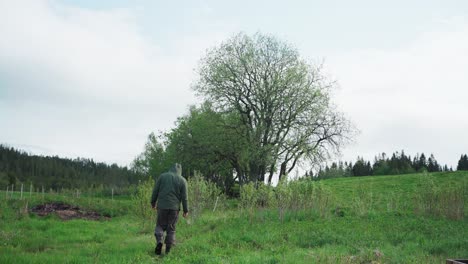 retrato de un hombre solitario con chaqueta con capucha en un paisaje de naturaleza verde