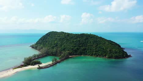 paradise tropical island with lush vegetation and trees forest in the middle of blue turquoise lagoon on bright cloudy sky