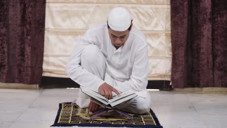 muslim man reading quran holy book at home in india