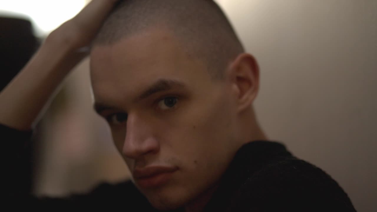 Upset Young Man Sitting On The Floor Leaning Against A Wall - Closeup Shot