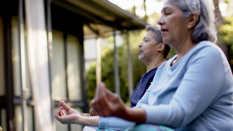 focused diverse senior couple practicing yoga meditation in garden