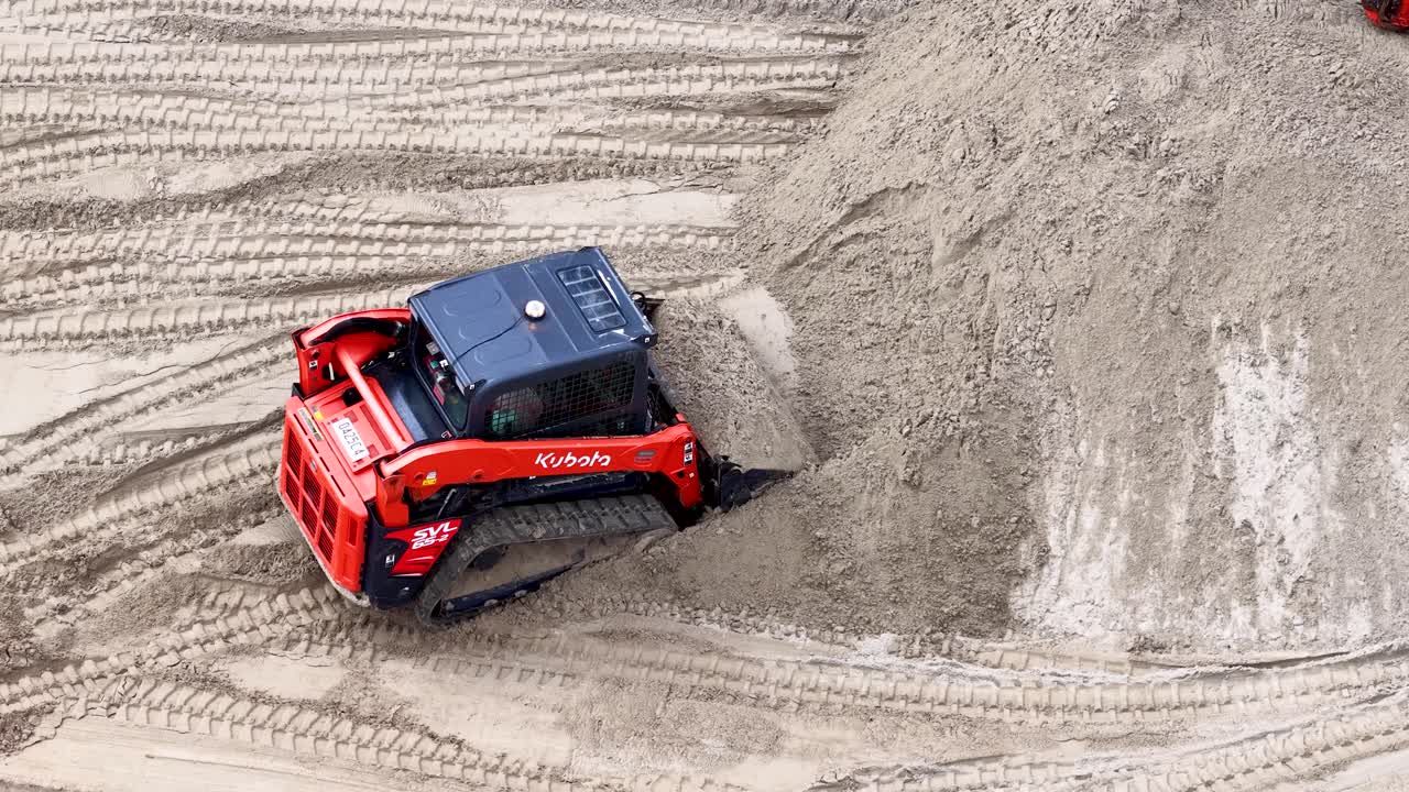 A red skid steer loader moves sand during a canal beach renovation in Australia