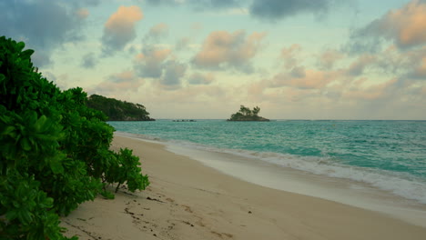 Toma-Estática-De-Mano-De-Una-Playa-Tropical-Al-Atardecer-Con-Un-Hermoso-Cielo-Nublado-Al-Atardecer