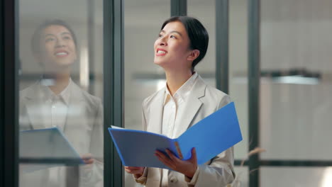 close up smiling a business woman holding folder with paperwork with review, contract and report in office at work. application, document and proposal with young female employee reading notes working