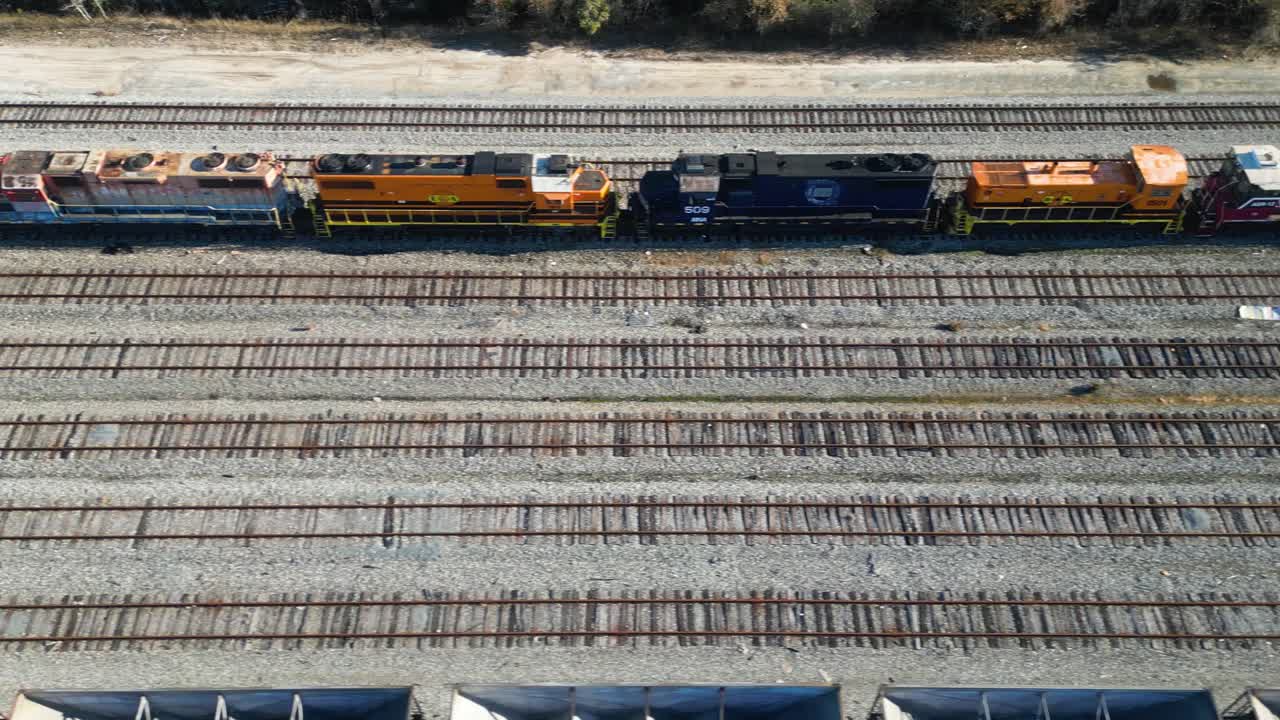 panning overhead drone view of various train engines in different states of disrepair sitting in shunting yard