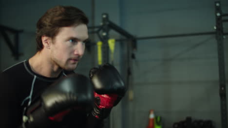 anxious sport man practicing kicks at gym. male boxer warming up in sport club