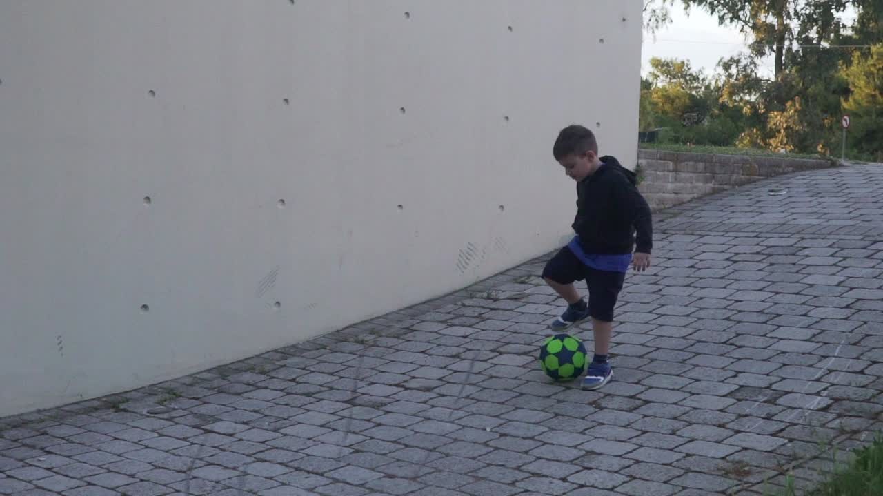 niño griego caucásico, jugando con una pelota al aire libre