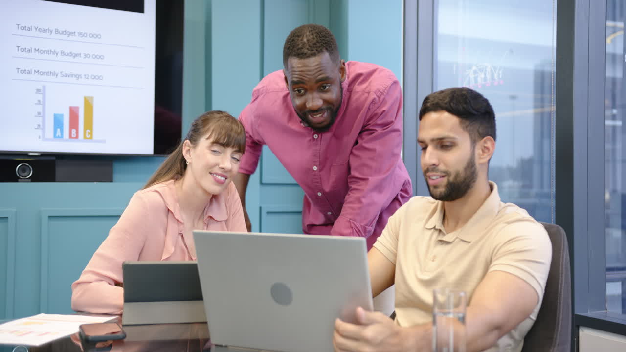 Working on laptops, diverse team smiling during business meeting in office