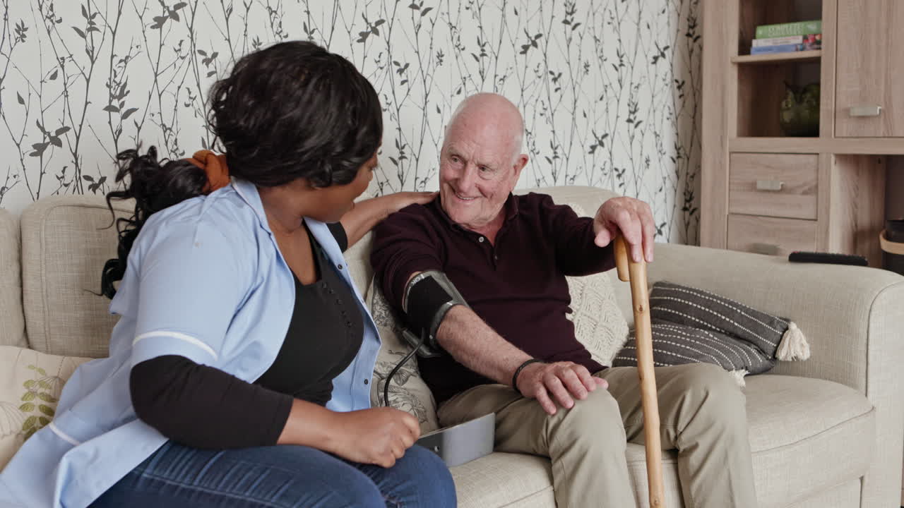 Caregiver Checking Elderly Man's Blood Pressure at Home