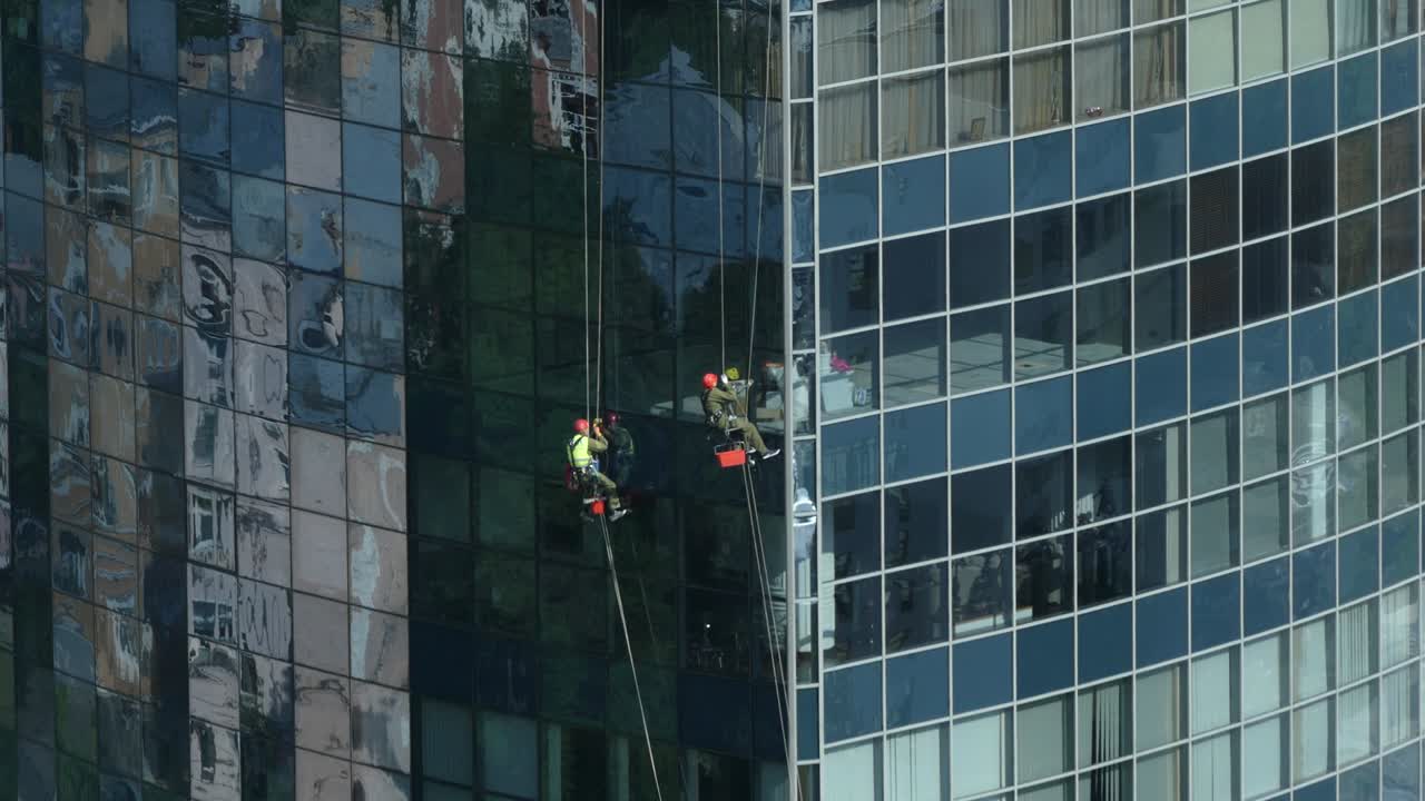 trabaja en alta altitud. un trabajador lava las ventanas de un rascacielos. el escalador lava ventanas en altura. un esturión lava ventanas de un rascacielo.