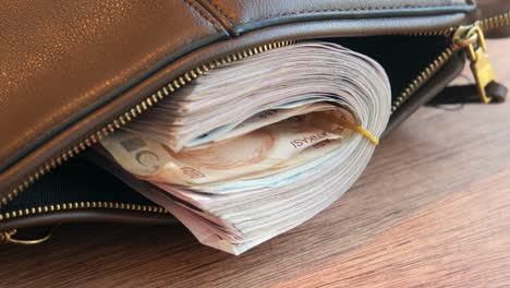 a stack of turkish lira in a brown leather bag