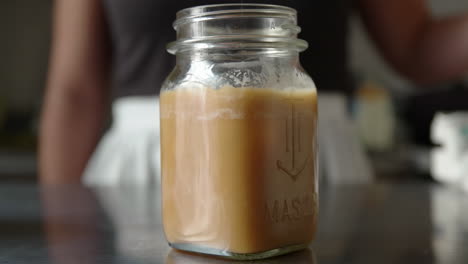 Woman-places-ice-cubes-in-creamy-coffee