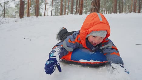 child sledding in snowy forest