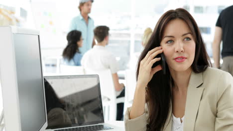 mujer trabajando en su escritorio hablando por teléfono
