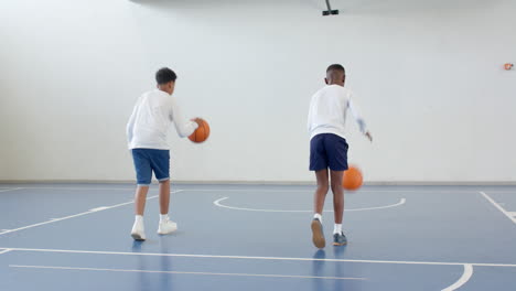 multiracial boys practicing basketball dribbling in school gym, focused on skills