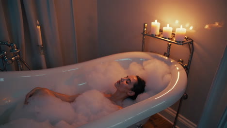 woman relaxing in a warm bath with candles