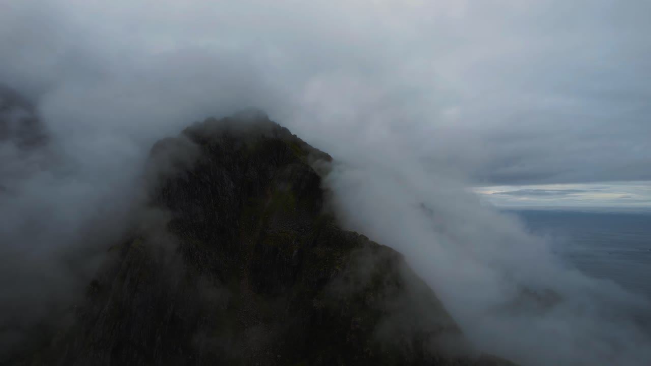 Cloudy mountain peak, scenic coastal landscape at Lofoten Islands, Norway. Green landscape, blue sea