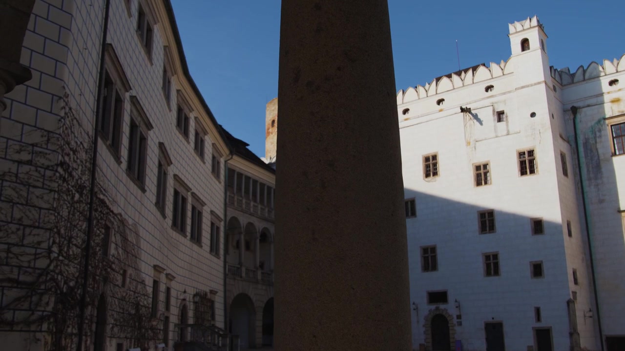 Movimento laterale della telecamera attraverso i pilastri di un porticato che rivela la torre e il cortile del castello di Jindřichův Hradec, Repubblica Ceca