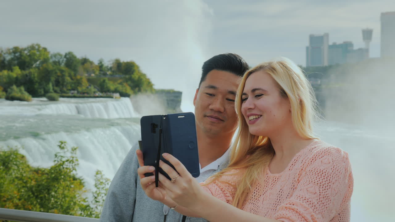 una joven caucásica de cabello rubio con su novio katai se toma una selfie por teléfono en niaga