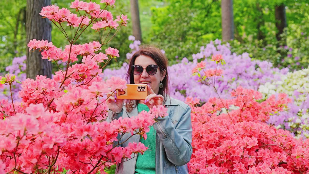 Momento de estilo de vida tranquilo enquanto um visitante fotografa flores em meio a cores vibrantes de jardim