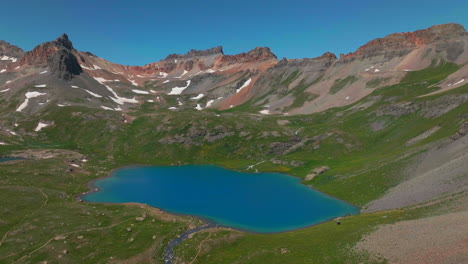 Luftdrohne-Filmisch-Große-Höhe-Tief-Himmelblau-Atemberaubendes-Eis-Seebecken-Inselsee-Silverton-Colorado-Atemberaubend-Himmlisch-Verträumt-Grüner-Sommer-Unglaubliche-Rocky-Mountains-Schnee-Schmelzender-Kreis-Links