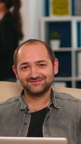 vertical video manager sitting on couch in front of camera smiling