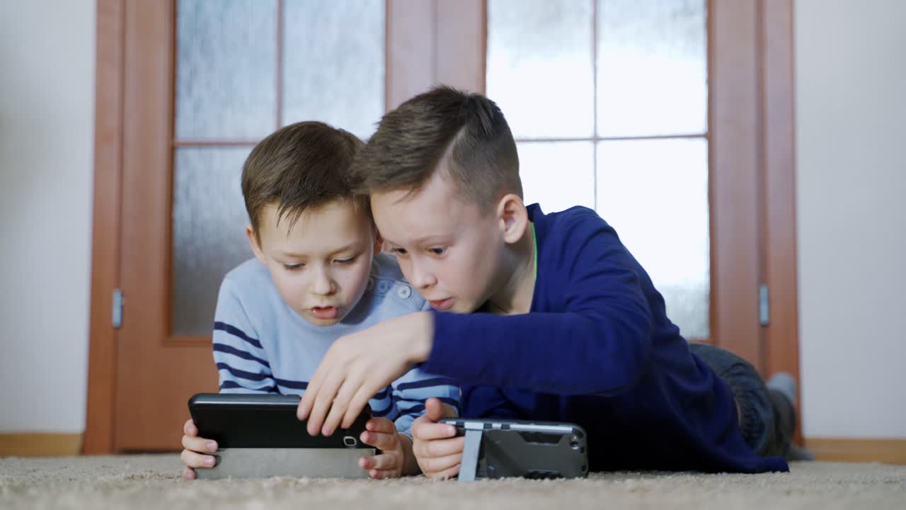 Two kids with gadgets. Brothers playing online games on smartphone at home, modern communication and gadget addiction concept