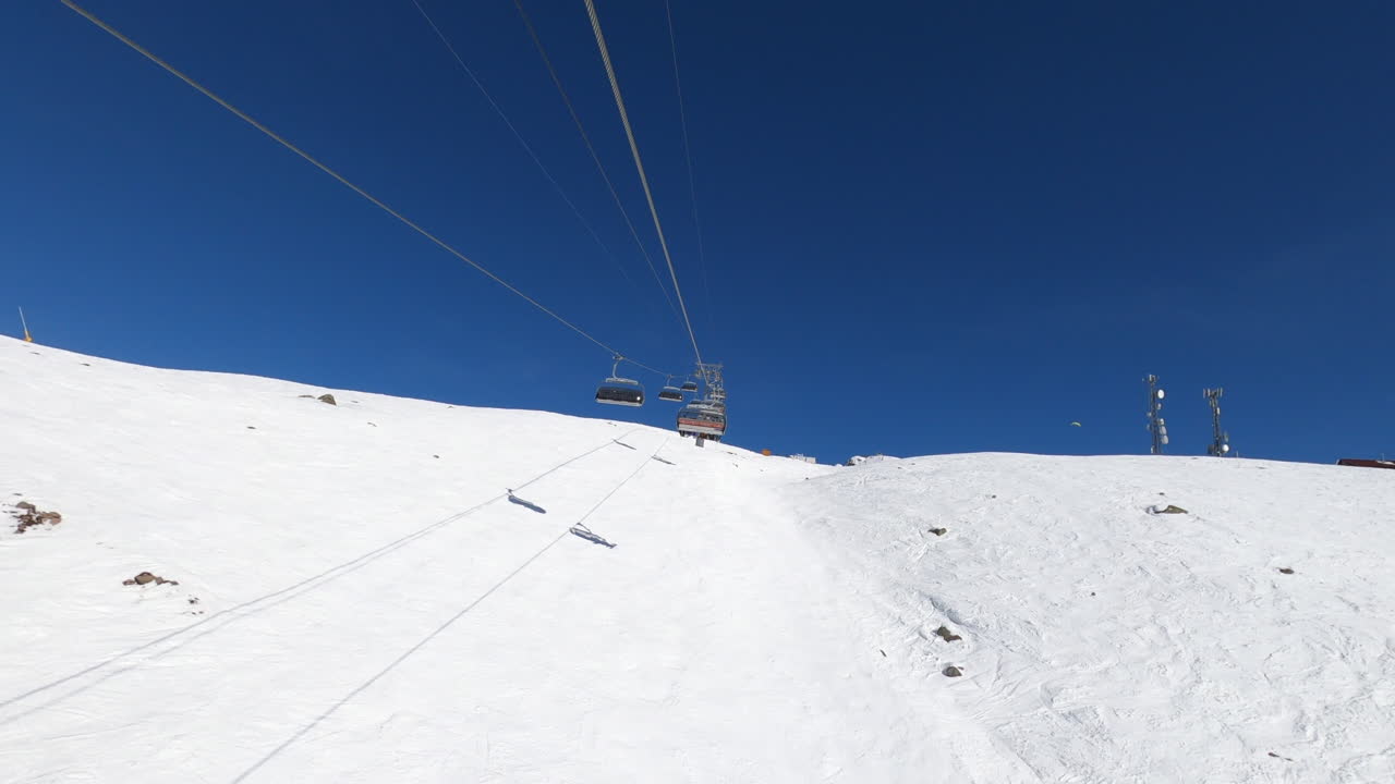 Hyperlapse: skier rides outdoor ski lift moving fast towards top of snow covered mountain