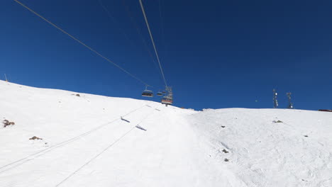 hyperlapse: skier rides outdoor ski lift moving fast towards top of snow covered mountain