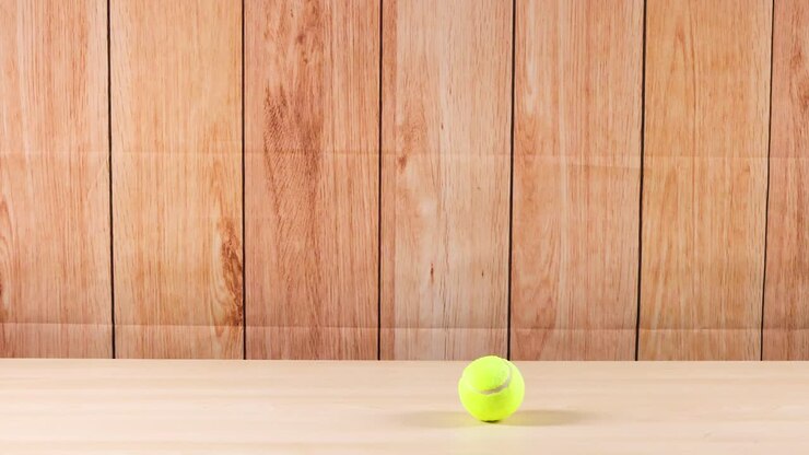 A tennis ball rolls across a wooden shelf